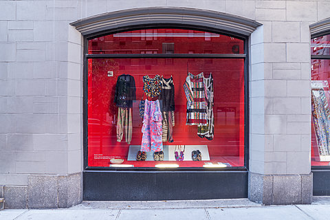 A window displaying various clothes hanging against a red background.