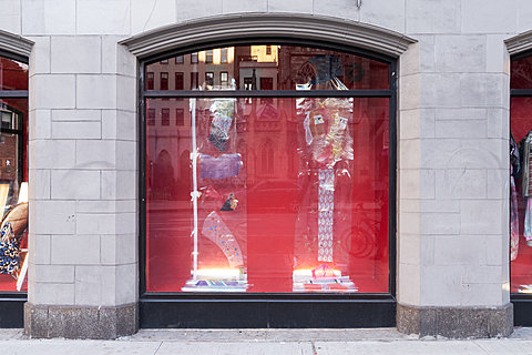 A window displaying various clothes in plastic displayed against a red background.