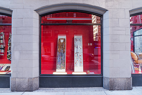 A window displaying various clothes in boxes leaning against a red background.