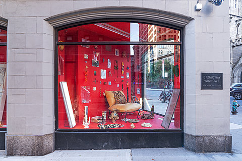 A corner window with various small items hung on a red background.