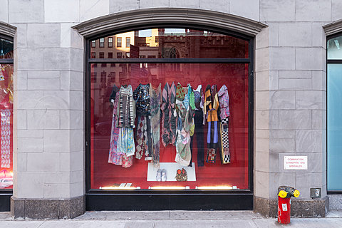 A window displaying various clothes hanging against a red background.