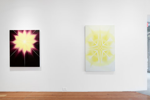 Installation image of two paintings in the exhibition. On the left, a purple background and a yellowish orange sun like shape. On the left, a very light yellow painting. 