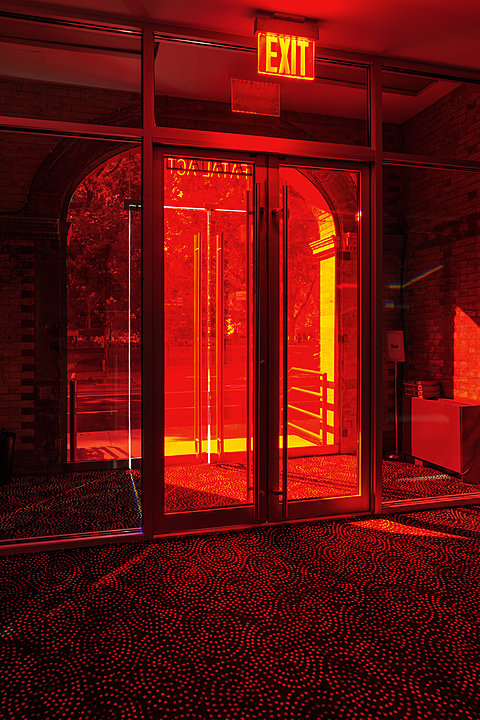 Light comes in through tinted red doors illuminating a patterned carpet.