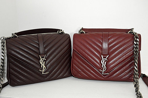 Two Yves Saint Laurent small leather handbags are placed next to each other. The one on the left is dark brown and the one on the right is vibrant red. They both have metal chains, and the "YSL" logo in the center.