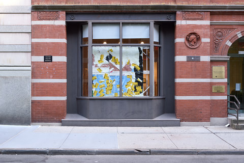 Image of the exhibition from street view featuring several large windows situated between to large brick walls. 