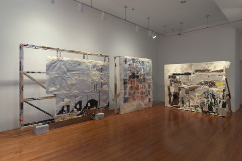 Installation image of two large, almost wall sized canvases standing upright in front of the white walls. 