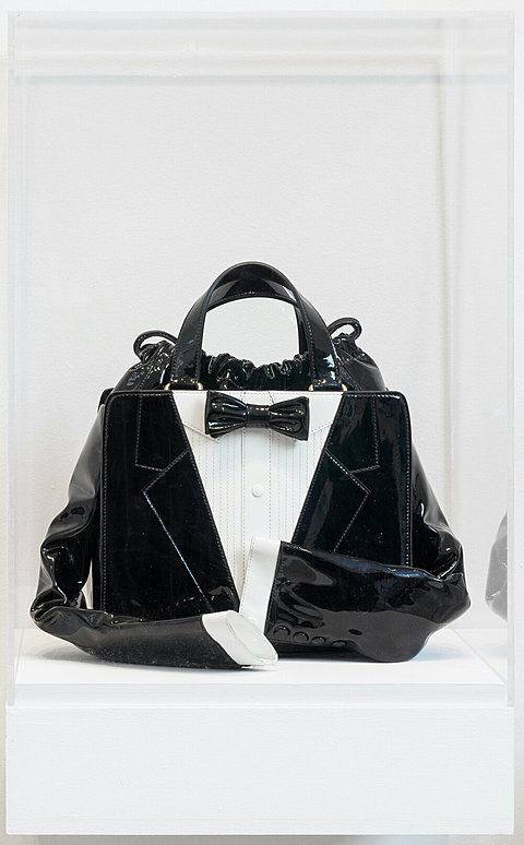 A black handbag in the shape of a tuxedo jacket with arms.