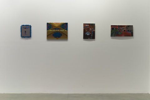 Installation view of four artworks hanging against a white wall in the exhibition space. The floor of the gallery is made of a grey cement. 
