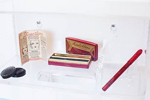 A display case holding a vintage mascara wand.