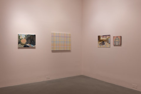 Installation view of two walls in the exhibition. The first painting, on the left, features a light orange spherical form on the left side of the canvas, there is a hole on top of the sphere. Emerging from the hole is a smoke of patterns in various colors. The rest of the painting, surrounding this sphere, is dark and filled with abstract forms in dark, shadowy colors. The next painting on the left, features light, pale, transparent, overlapping stripes in a weaving pattern. The purple, blue, pink, orange, and yellow lines overlap and create a checkered/woven pattern on the canvas. The first painting on the right side wall, features  features what seems to be a journal and an iPhone on a table with a lemon-printed table cloth. The next image features a box like figure with eyes, hair flowing from the sides of the box. The paintings are hung on a pale pink wall. 