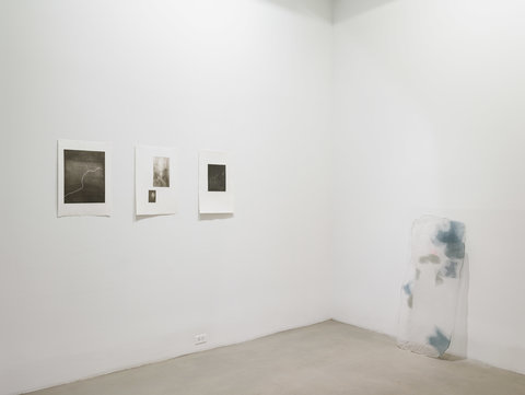 Installation view of three works on a wall in the exhibition and one work on the floor, leaning against the wall. 