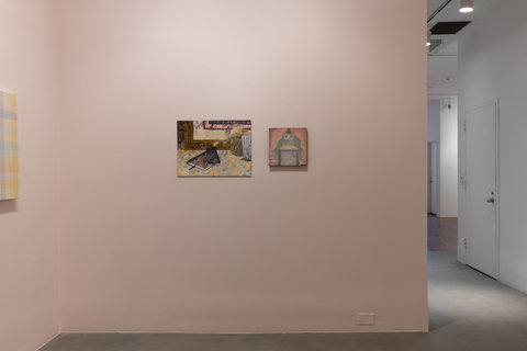 Installation view of two paintings in the exhibition. Two paintings are hung on a light pink wall. The first work, larger than the second, features what seems to be a journal and an iPhone on a table with a lemon-printed table cloth. The next image features a box like figure with eyes, hair flowing from the sides of the box. 