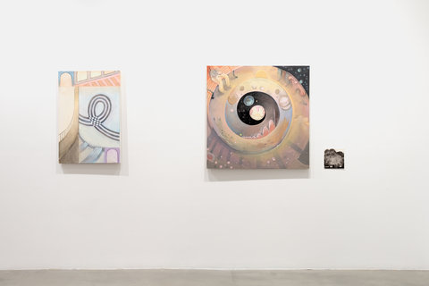 Installation view of three works in the exhibition hung on a white wall. The first work, on the left, features a abstract canvas of architectural elements. There is a black and white striped loop in the center of the work. Window like openings and beams line the top and bottom of the canvas. On the left side of the canvas a grey bridge leads to nowhere. The entire work is done is pale, pastel colors of purple, black, blue, orange, yellow, and orange. The image on the right features a layered spiral path, going down into what appears to be the universe, with planets, stars, marked at the end of the spiral. On the left side of the painting at the beginning of the spiral path, there is a figure seated on a park bench. On the work next to this, the rightmost work, is a small black and white sketch of a figure with eyes peering at the viewer. 