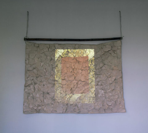 Installation view of the exhibition featuring a projection onto a fabric, textured structure that hangs from the ceiling like a projector screen. 