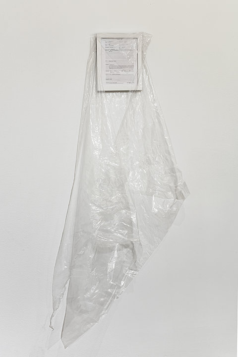 A small framed white image draped with clear plastic
