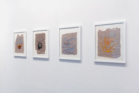 Installation view of four white, framed paper works in the exhibition. 