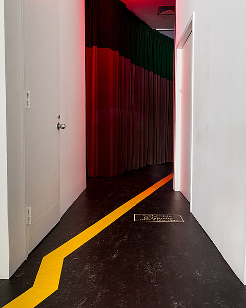 A yellow path on the black floor leads down a corridor to a red curtain.