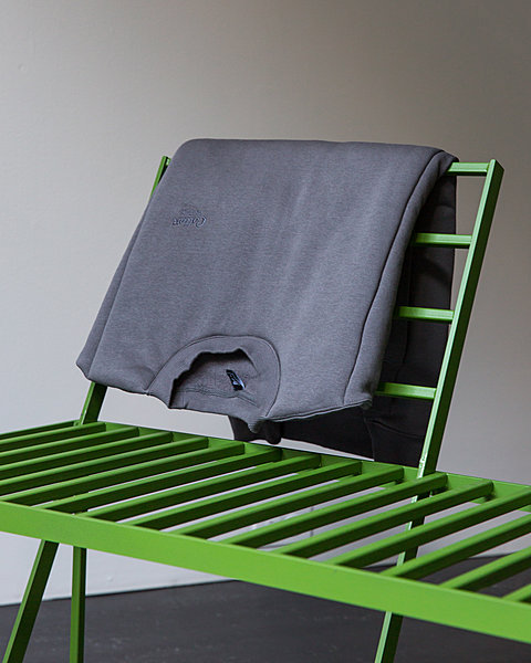 A folded sweatshirt embroidered "Cotton Traders" rests on a green bench.