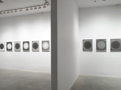 Installation view of two spaces in the exhibition. On one side of a white wall, there are six framed works of art. They consist of different combinations of black and white dots against a black or white background. On the right side of the wall, there are three more of these images. 