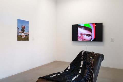 Installation image of the exhibition featuring two walls and a sculpture in the foreground with two works on the wall behind it in the background.
