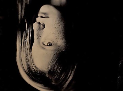 Image of a portrait of a girl. The image is flipped upside down. The girl has her hair covering half of her face.