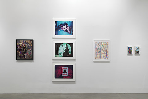 Seven colorful wall artworks hang on a white gallery wall.