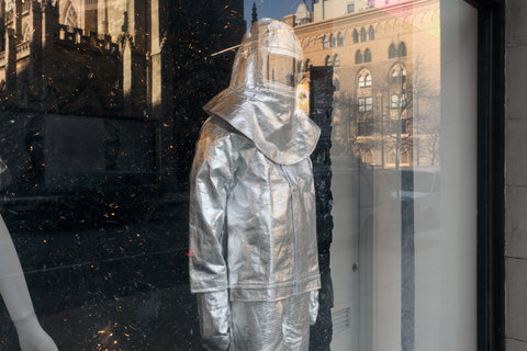 Image of a mannequin in the exhibition wearing a silver space-like suit with a fabric helmet. 