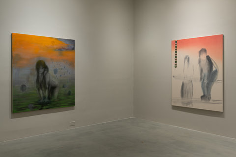 Installation view of two paintings on two walls in the exhibition. The walls are painted grey and converge at the corner.  Hanging on the left wall is a painting featuring orange skies that bleed into the rest of the painting of a figure on all fours in minimal color palette. On the right wall, a large painting is hung, again with the orange skies bleeding into the scene below which features two blurry figures.   