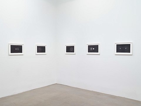 Five framed images of white circular shapes on black backgrounds hang on the walls.