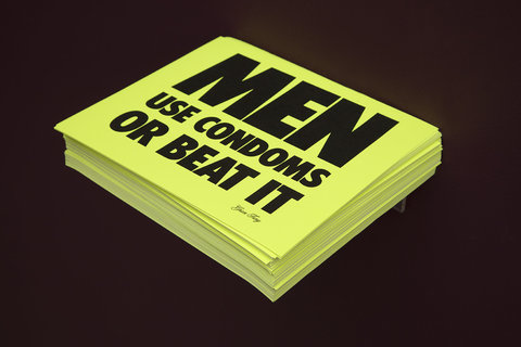 A neon green stack of paper that says "men use condoms or beat it."
