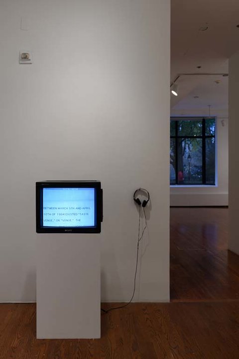 Installation view of the exhibition featuring a television monitor on a white pedestal. 