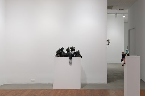Installation image of two white pedestals in the exhibition. Sculptures sit atop the pedestals. 