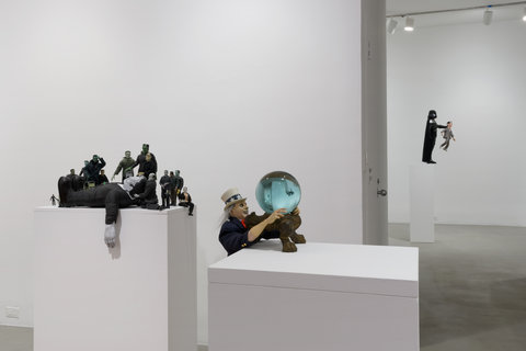 Image of two white pedestals in the exhibition in the foreground of the installation image. Sculptures sit atop the pedestals. In the background, another sculpture stands atop a white pedestal. 