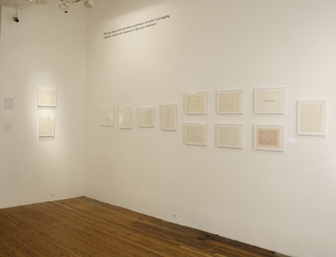 Gallery installation image of many pieces of white paper. On the left wall there is one piece of white paper. On the adjacent wall, there are three white works and then six white works grouped in an arrangement of two by three, followed by one white image.  