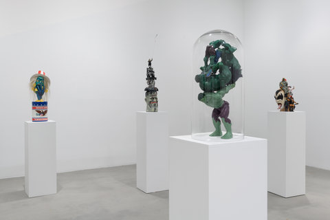 Image of four sculptures in the exhibition scattered around the room atop white pedestals. 