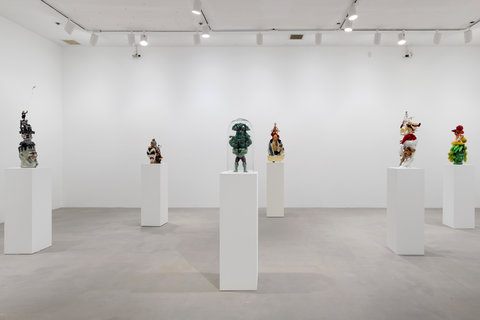 Image of six sculptures in the exhibition scattered around the room on white pedestals. 