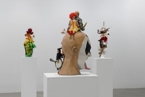 Installation image of three sculptures in the exhibition scattered around the room on three white pedestals. 