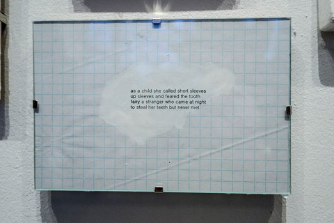 Close-up image of a work in the exhibition including a white piece of paper with a grid and a poem typed out onto it. 