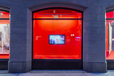 A television monitor hangs against a red background.